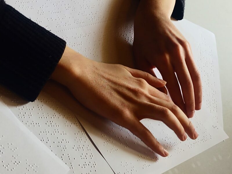 Χέρια πάνω σε χαρτί Braille που διαβάζουν κείμενο.