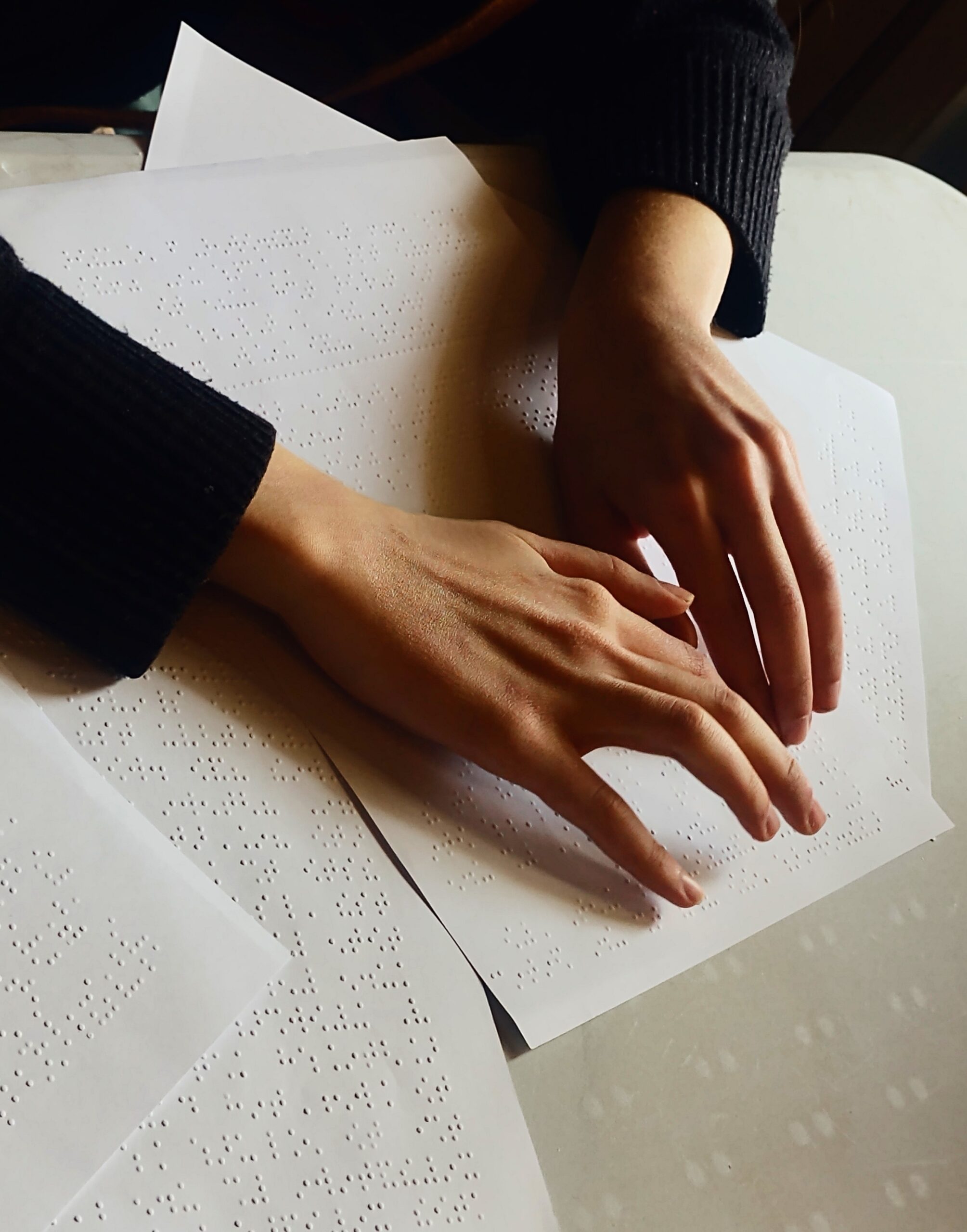 Χέρια πάνω σε χαρτί Braille που διαβάζουν κείμενο.